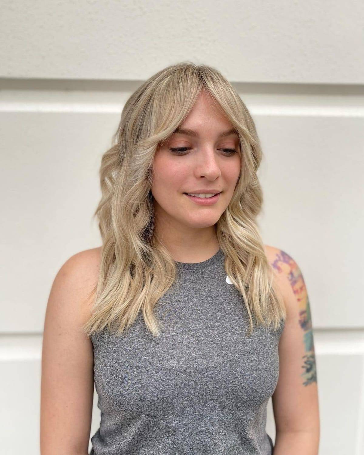 Coiffure blonde ondulée avec franges en rideau