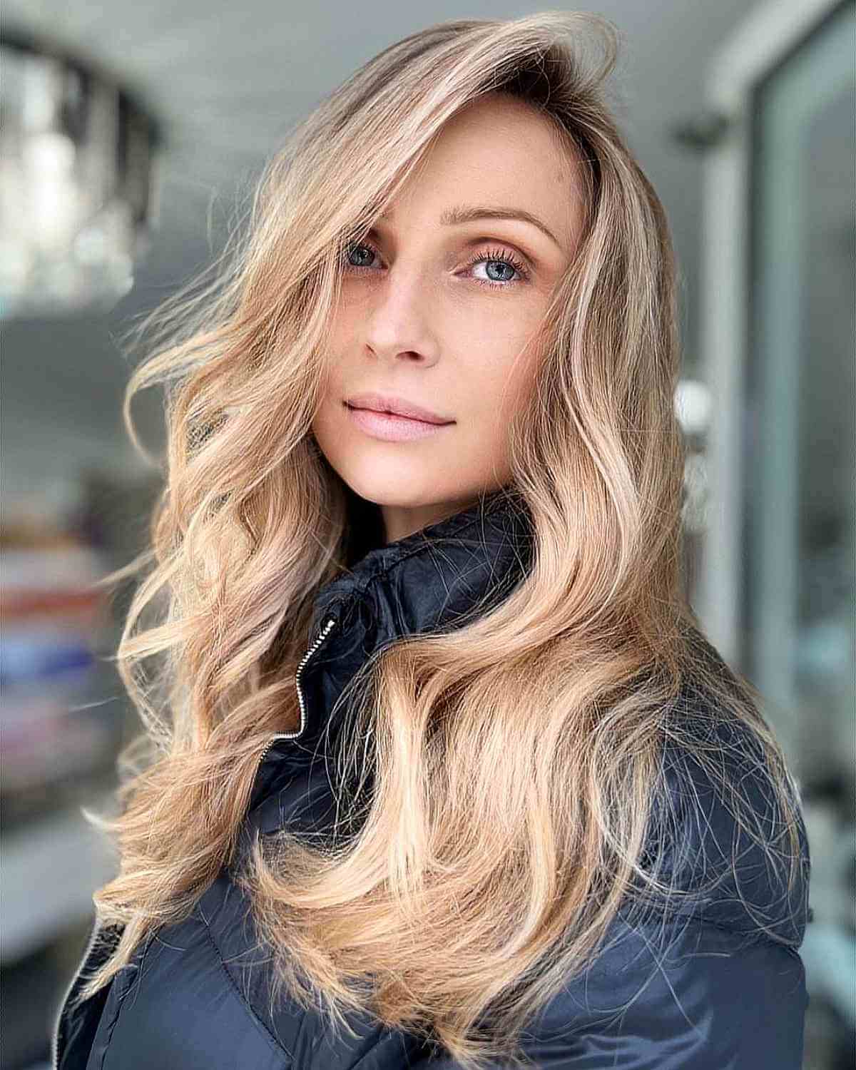 Cheveux longs ondulés balayés sur le côté avec une raie sur le côté.