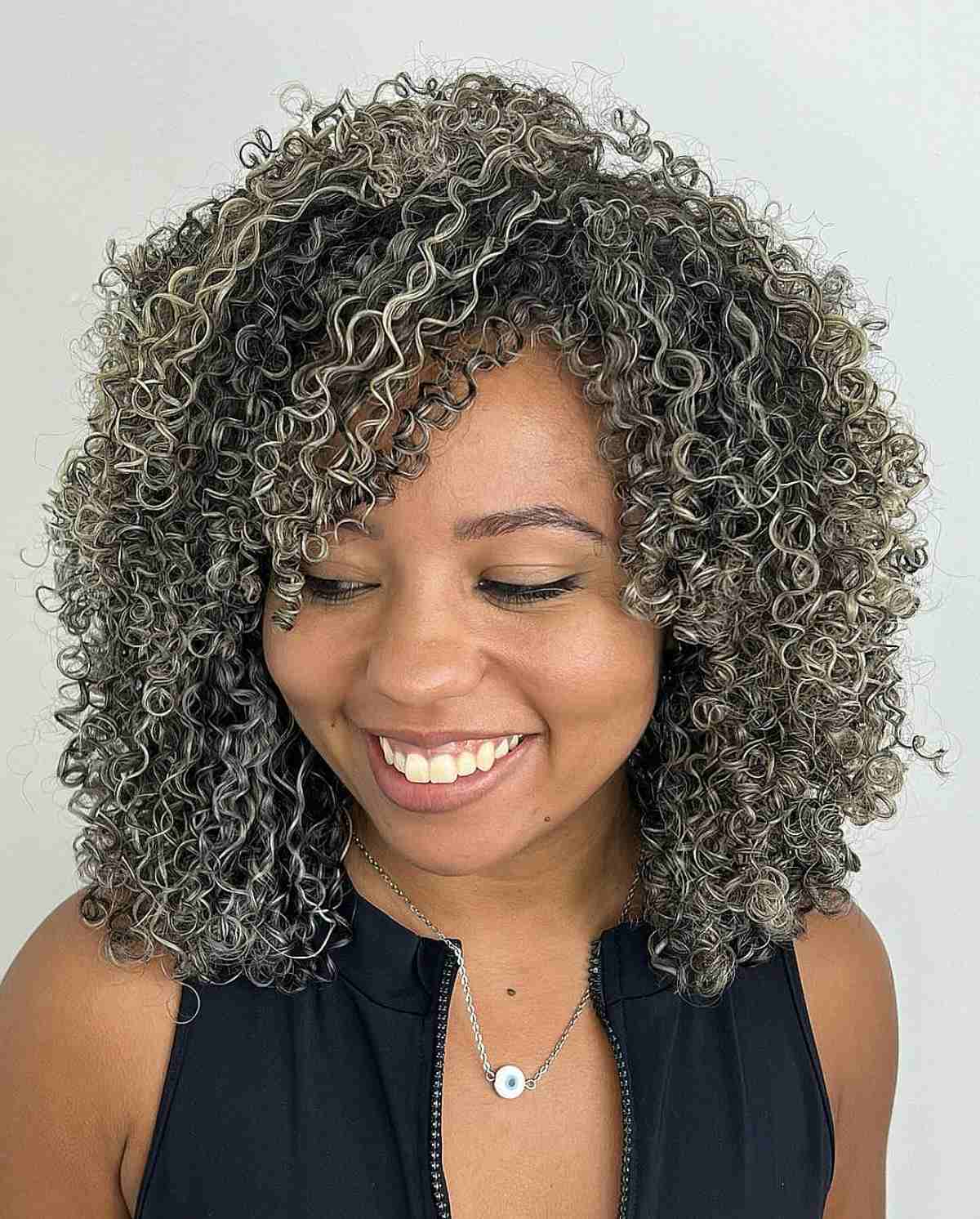 Une femme avec une coupe Cadō comprenant des boucles superposées et des mèches grises qui définissent les boucles et ajoutent du volume.