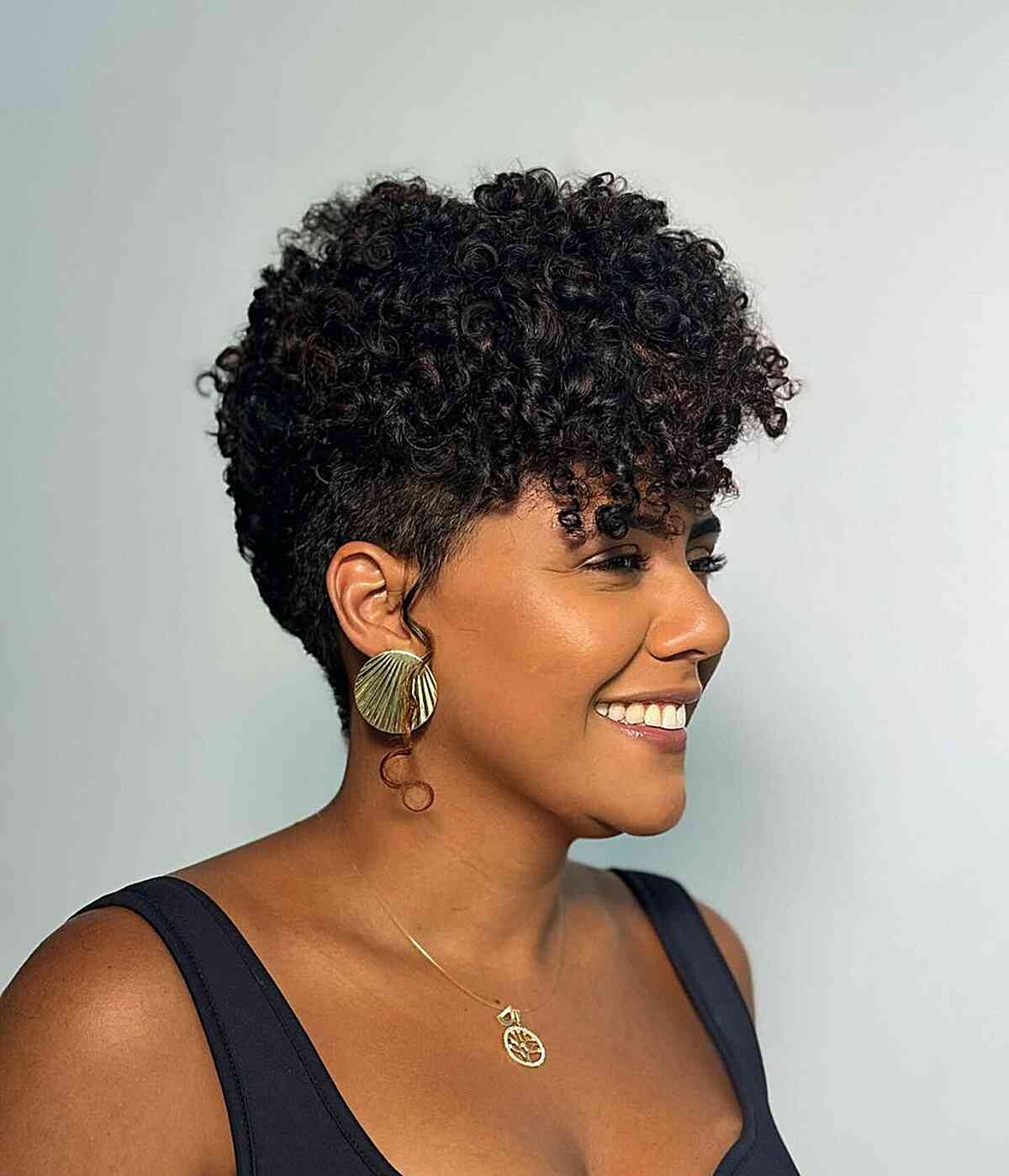   Une femme au visage en forme de cœur présentant une coupe pixie avec une frange, parfaite pour des boucles en spirale, avec des mèches subtiles ajoutant de la dimension.