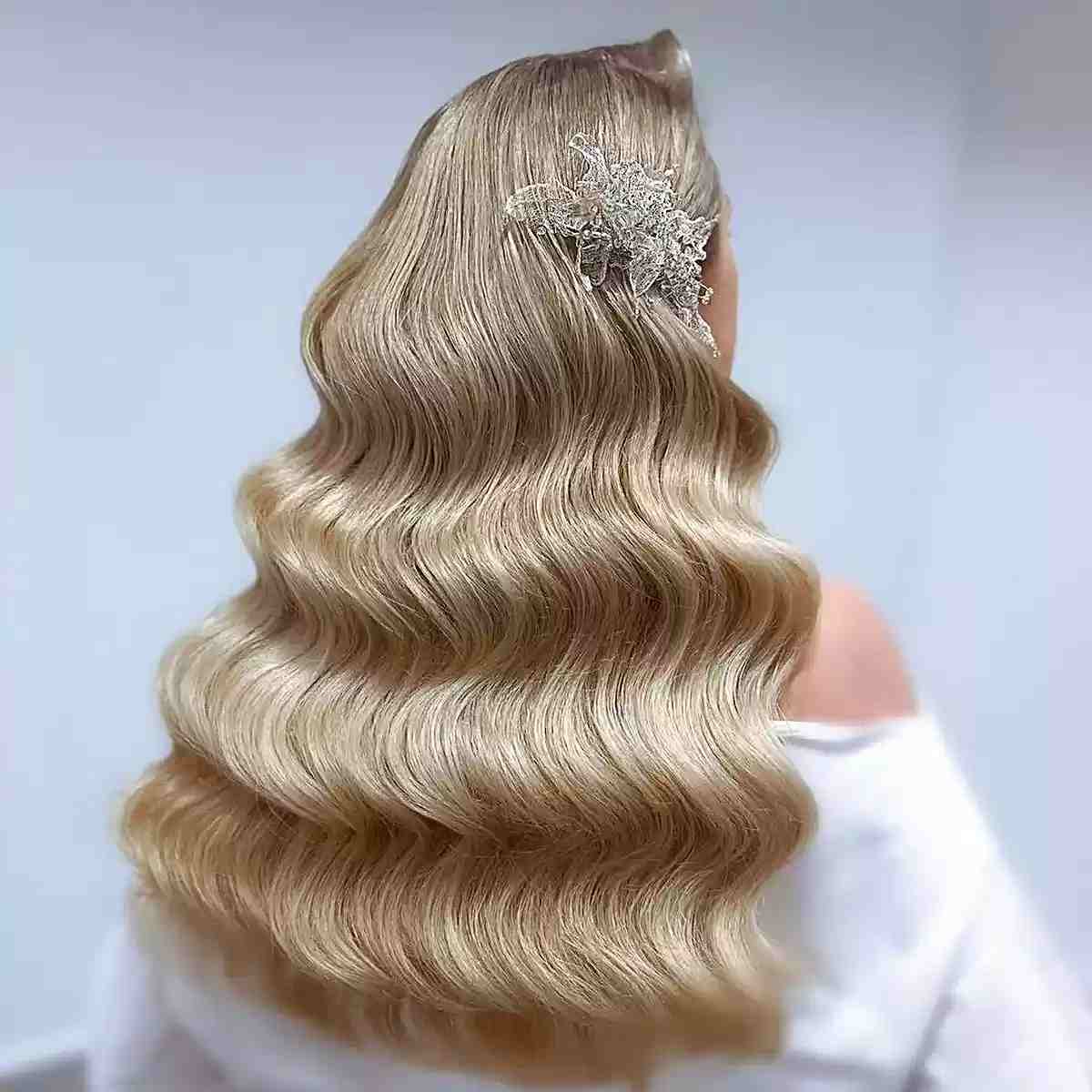 Longues ondulations hollywoodiennes blondes et glamour avec barrette