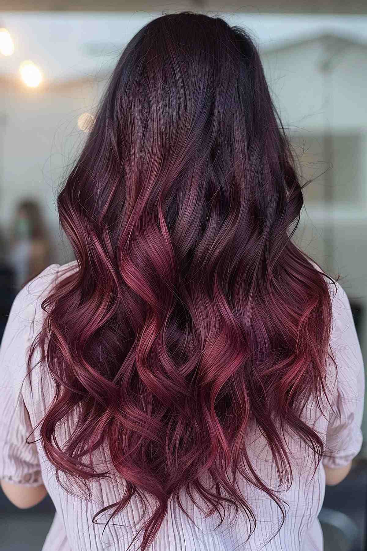Ombre de chocolat noir à cerise sur de longs cheveux ondulés.