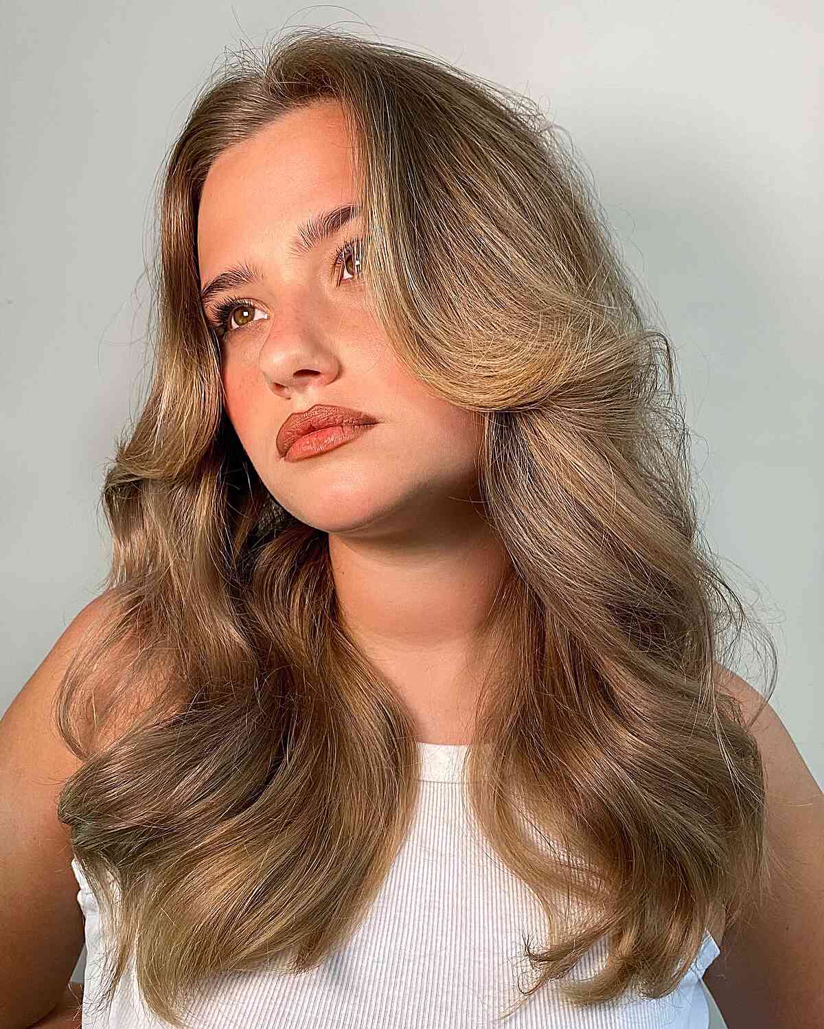 Cheveux ondulés mi-longs des années 90 avec effet plume