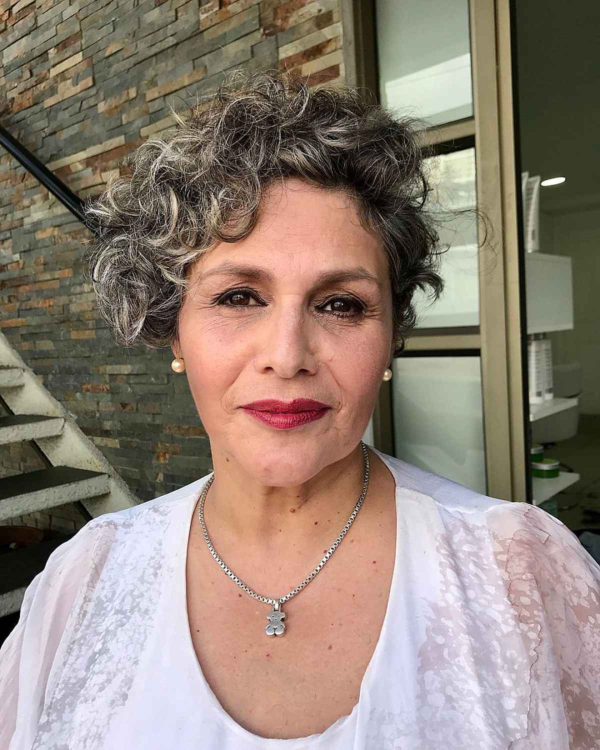 Bob asymétrique bouclé pour une femme de soixante ans aux cheveux courts.