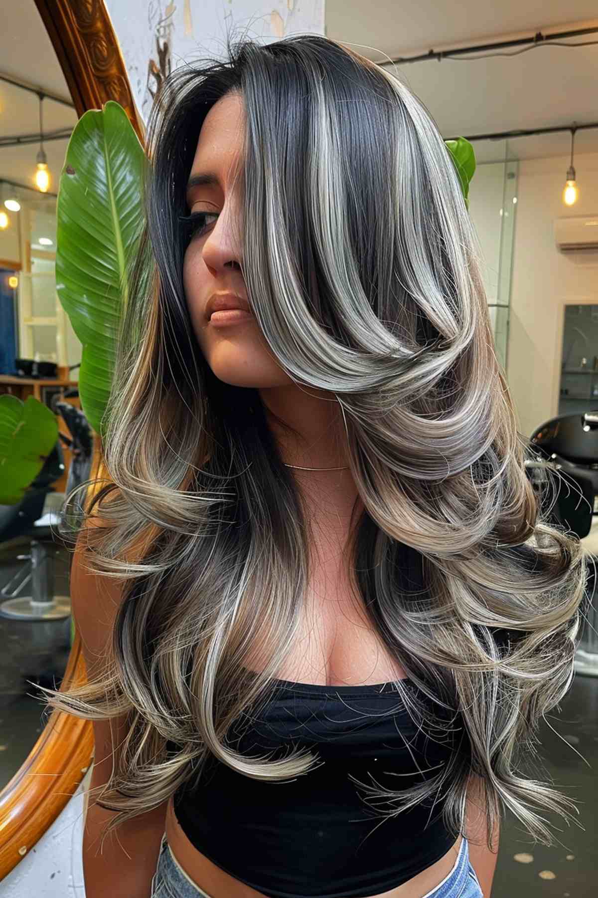 Longs cheveux épais avec des reflets blonds cendrés et de grosses boucles.