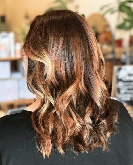 image vue de côté d'une femme aux cheveux ondulés avec balayage dans des couleurs de cheveux blond miel