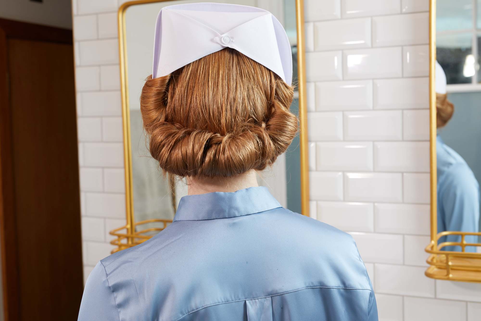 Une femme aux cheveux roux coiffée en infirmière inspirée de Ratched Updo 