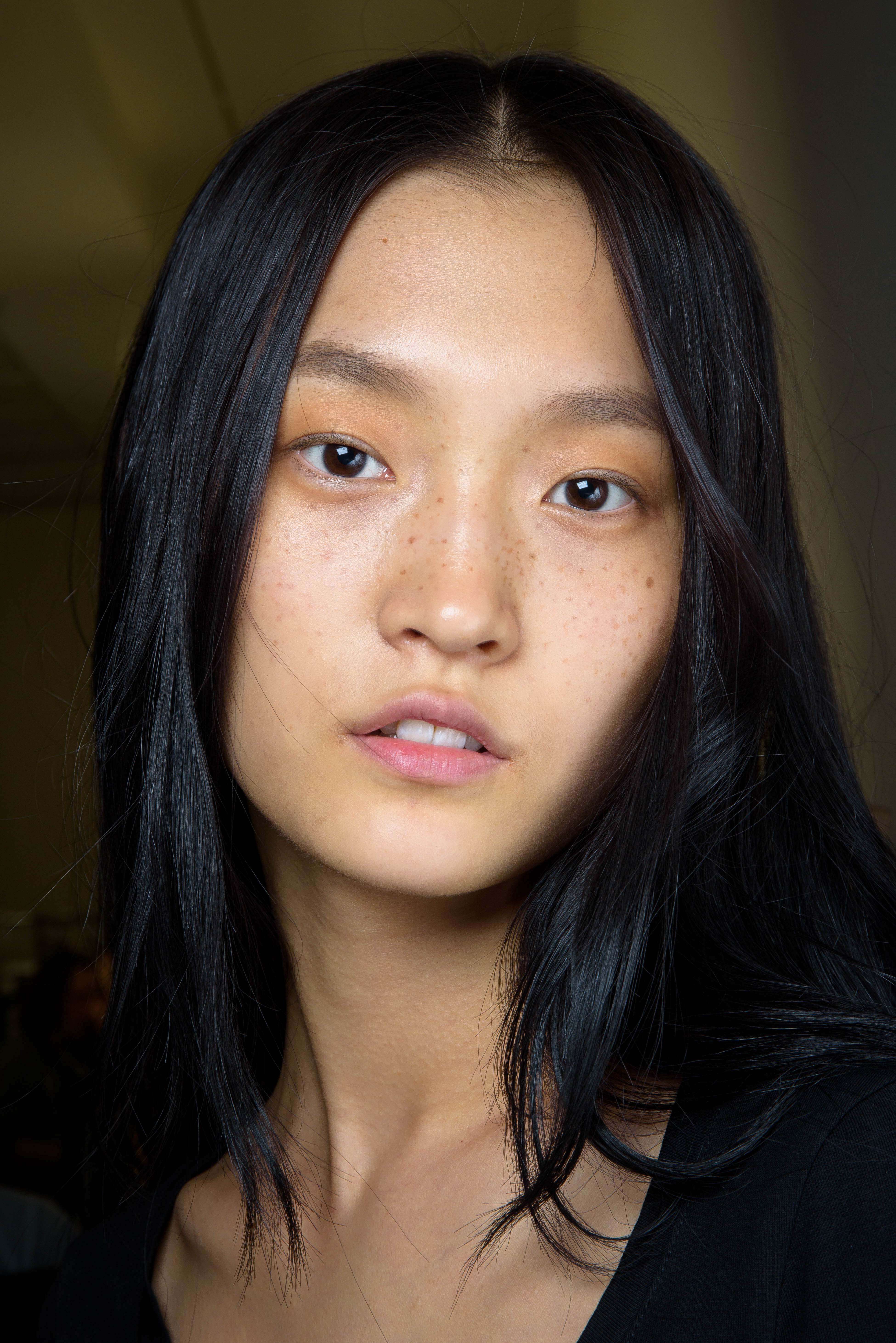 Coiffures asiatiques : Modèle asiatique aux cheveux bruns brillants et raides, portant un haut noir.