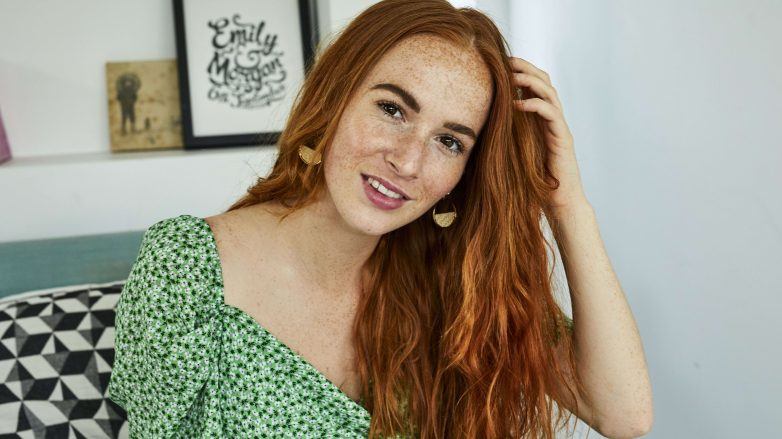 Femme touchant ses longs cheveux roux ondulés