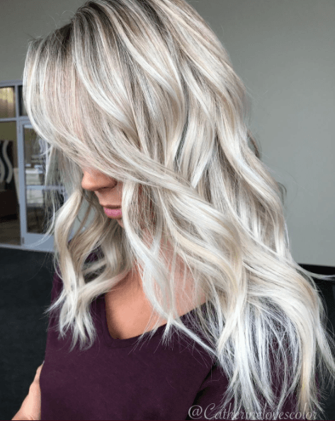 Nuances de cheveux blonds : Femme aux longs cheveux ondulés blancs comme la glace, portant un haut noir.