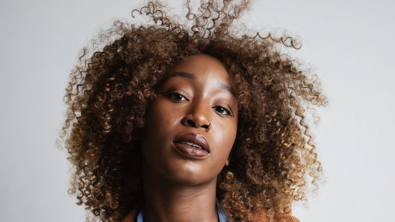 Femme avec des reflets marron clair et dorés sur des cheveux 3C