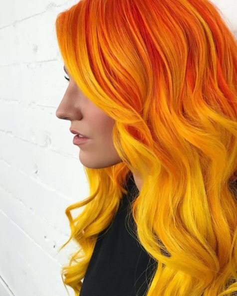 vue de côté d'une femme aux longs cheveux ondulés jaune-orange