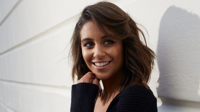 Brune avec un bob ondulé appuyé sur un mur