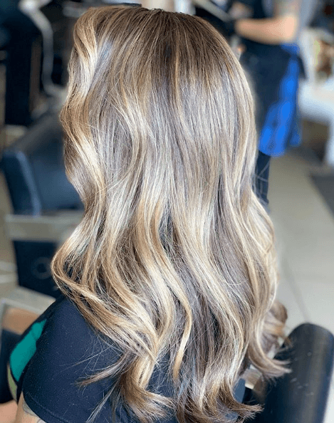 Points forts partiels : Vue de dos d'une femme aux cheveux ondulés d'un blond cendré clair avec des mèches partielles